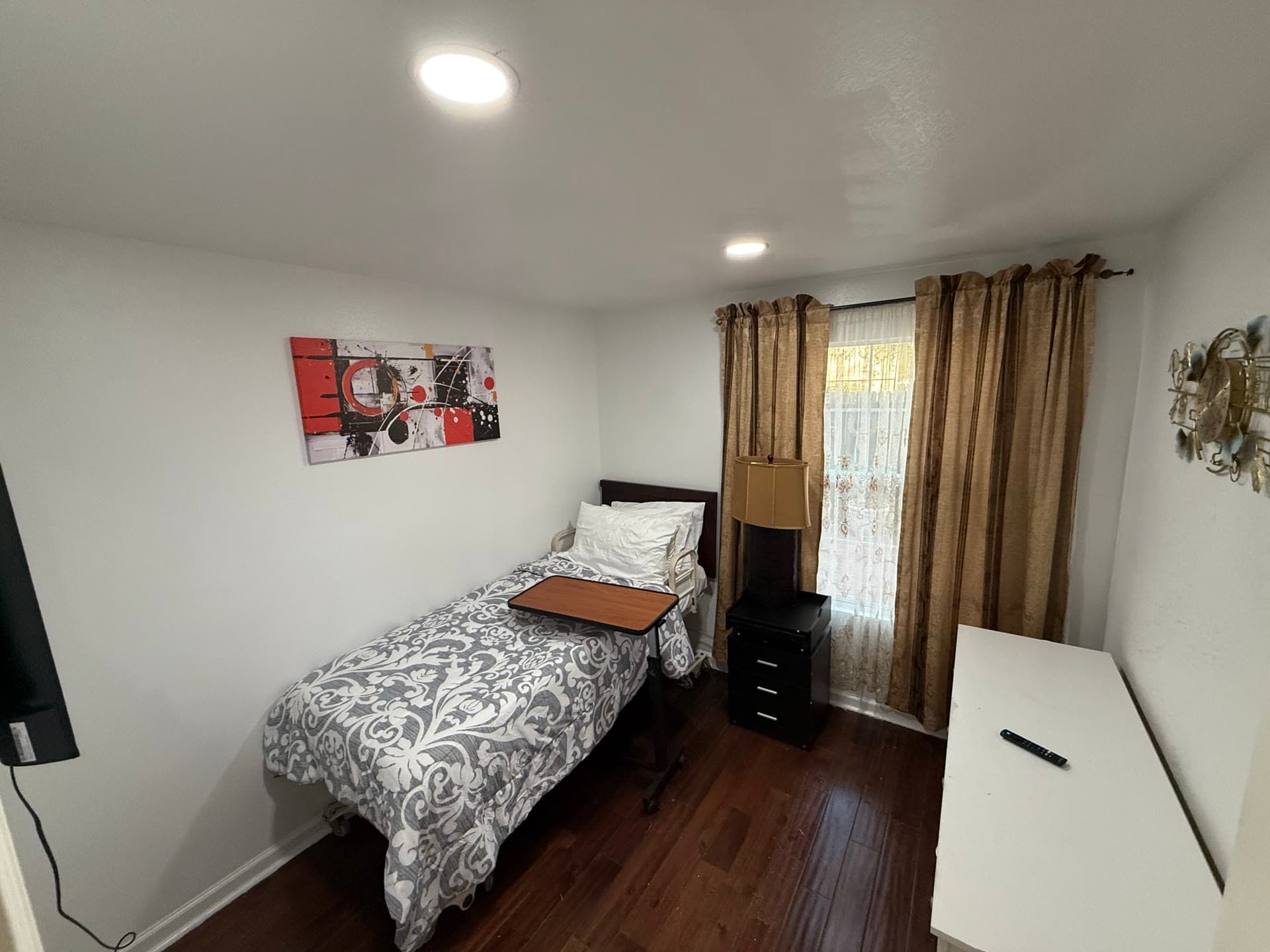 Cozy room with patterned comforter, dark wood floors, and abstract art
