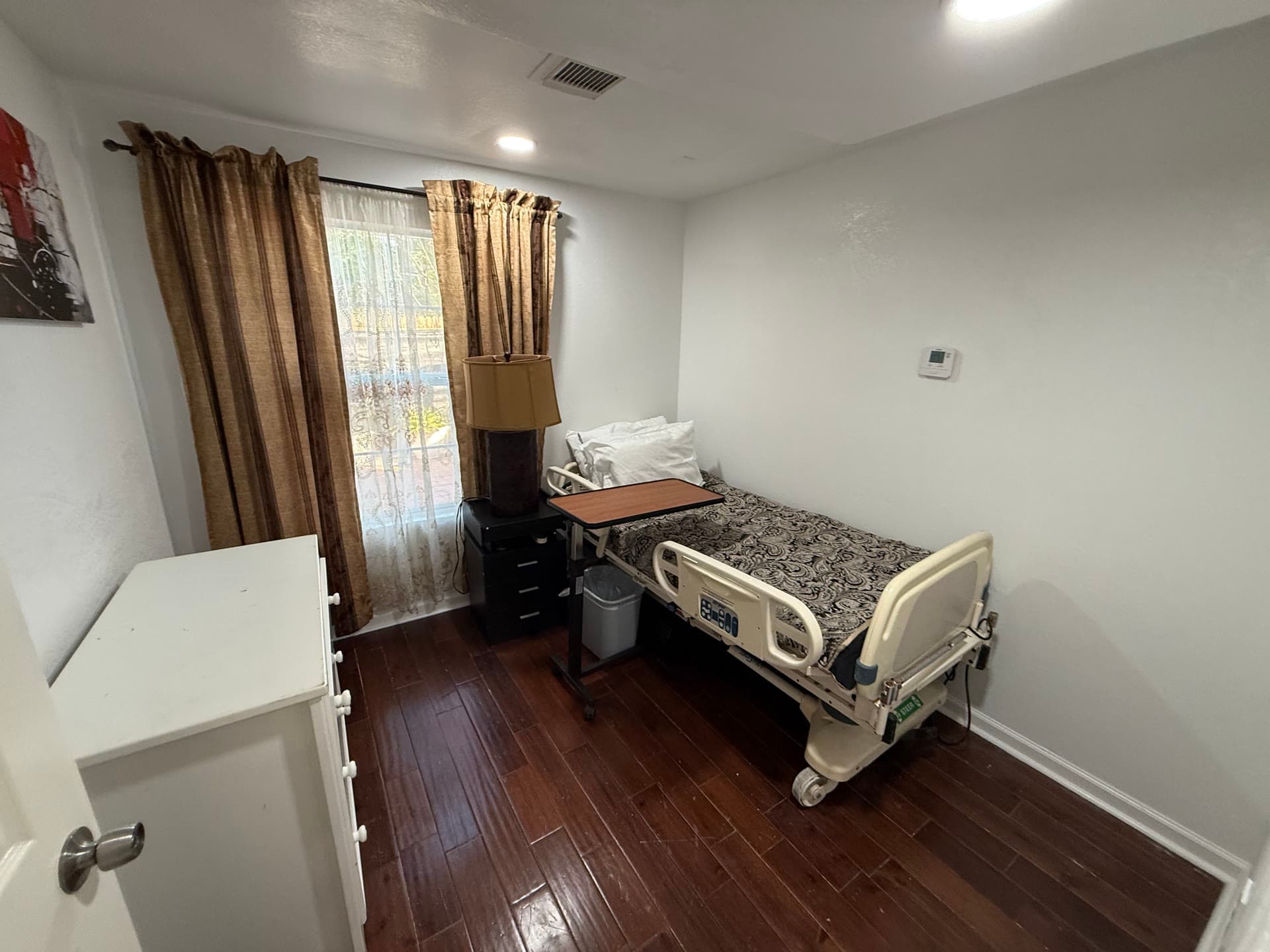 Comfortable room with patterned comforter, gold curtains, and bedside table