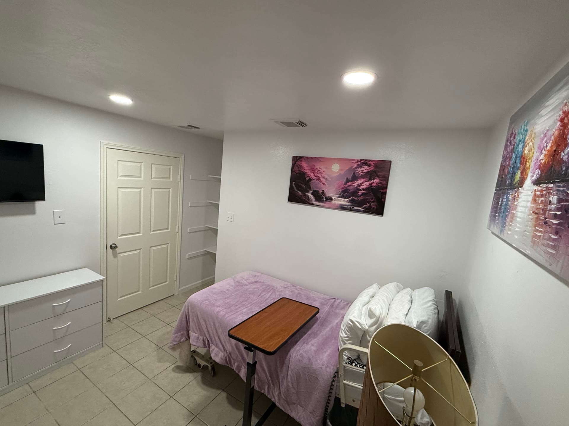 Bedroom with white dresser, TV, closet, and pink moonlight painting