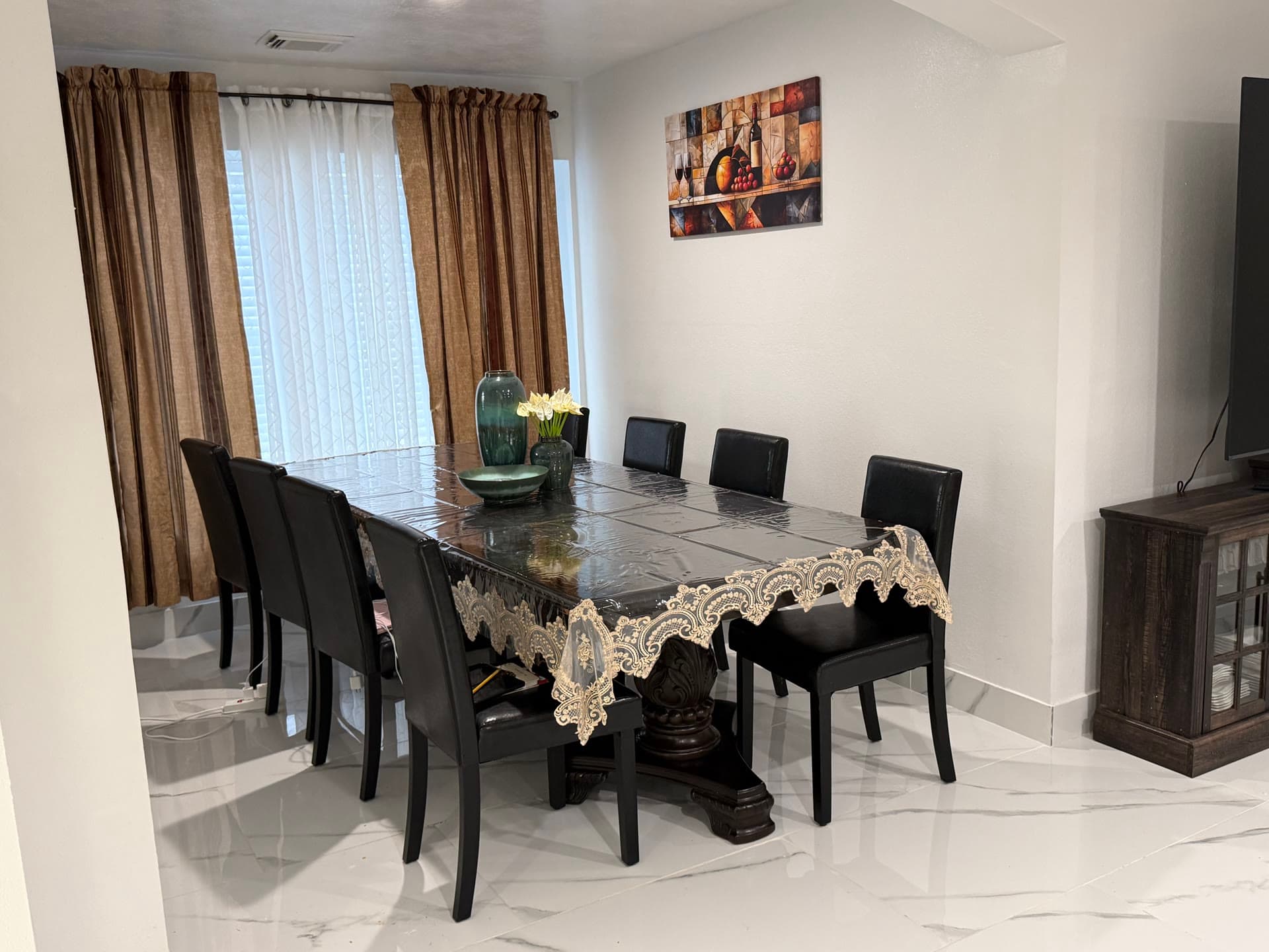 Dining room with elegant dark table, leather chairs, and gold curtains from living area