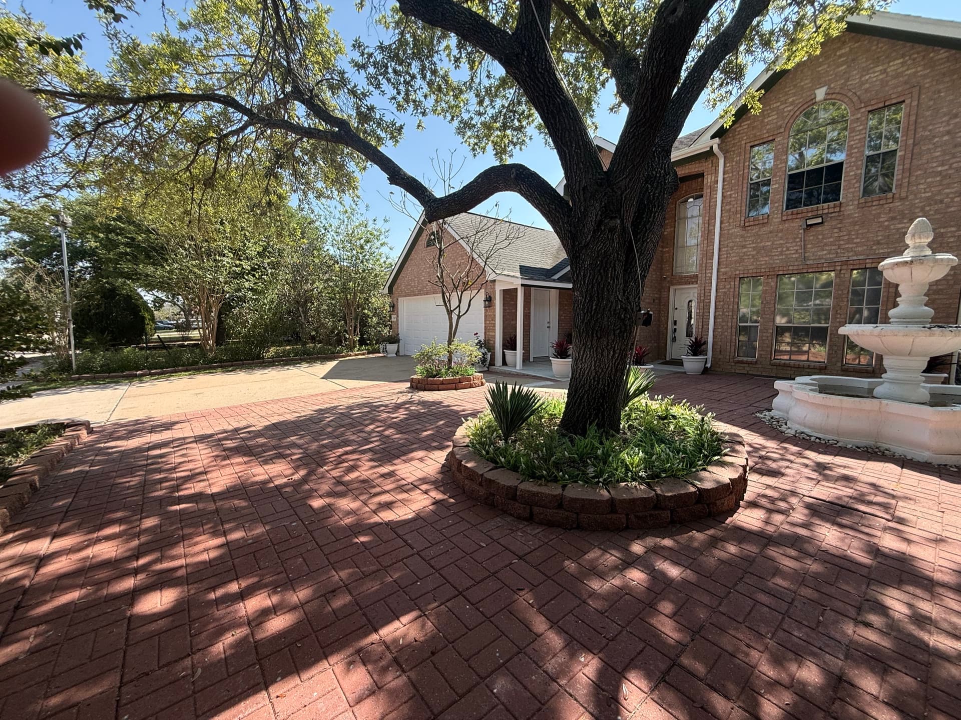 Front yard with oak tree, fountain, and brick pavers