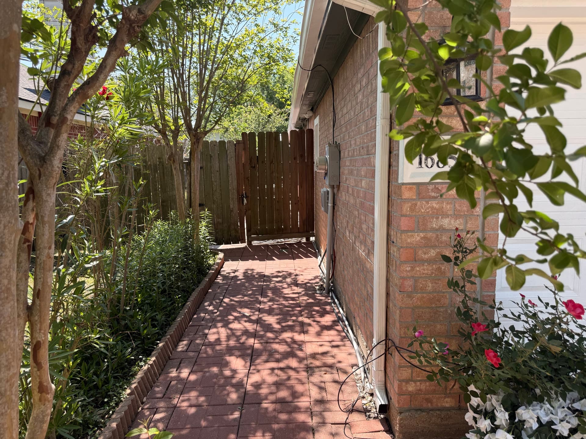 Side walkway with brick path leading to backyard