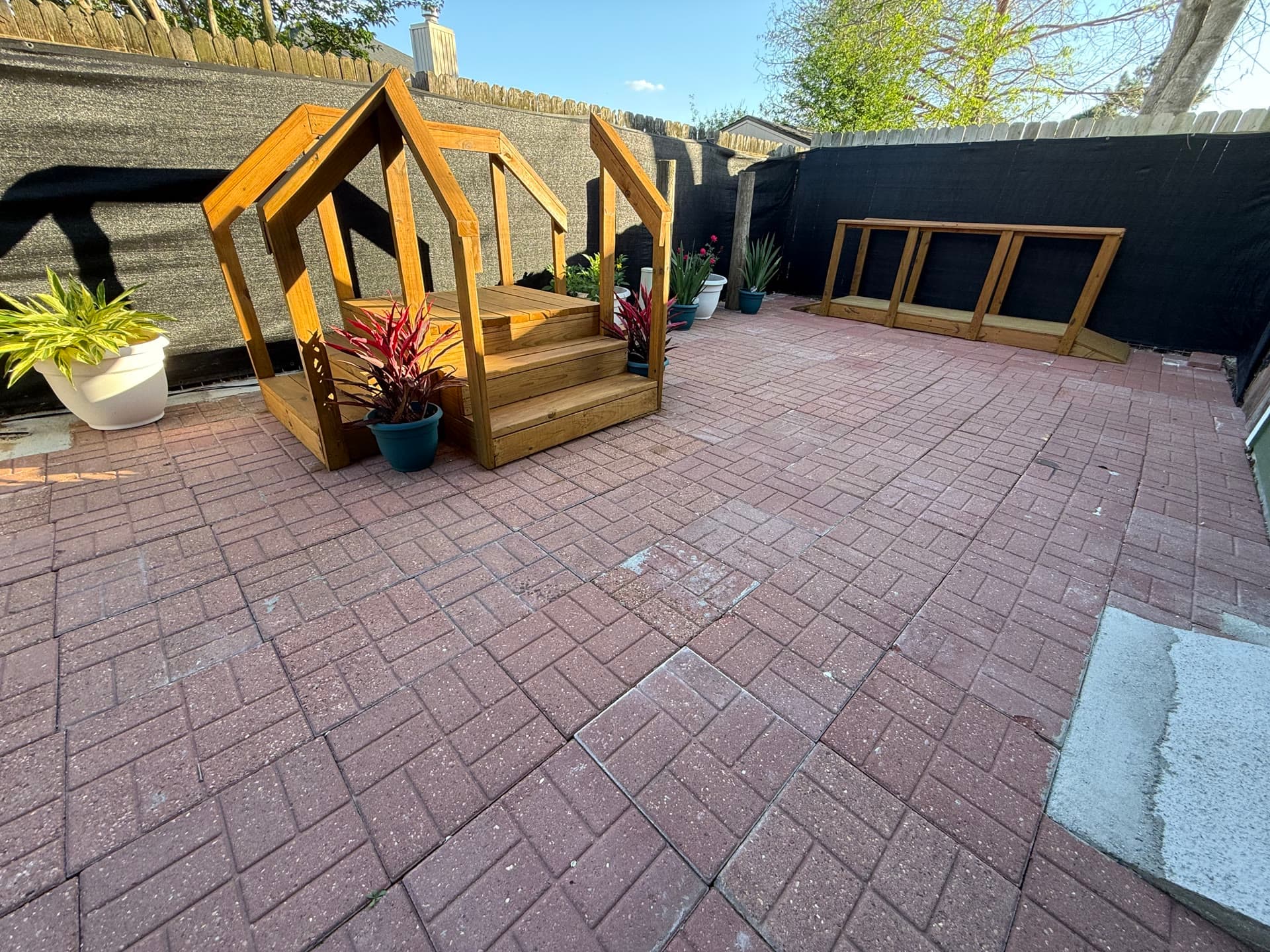 Brick patio with decorative wooden deck entrance and planters