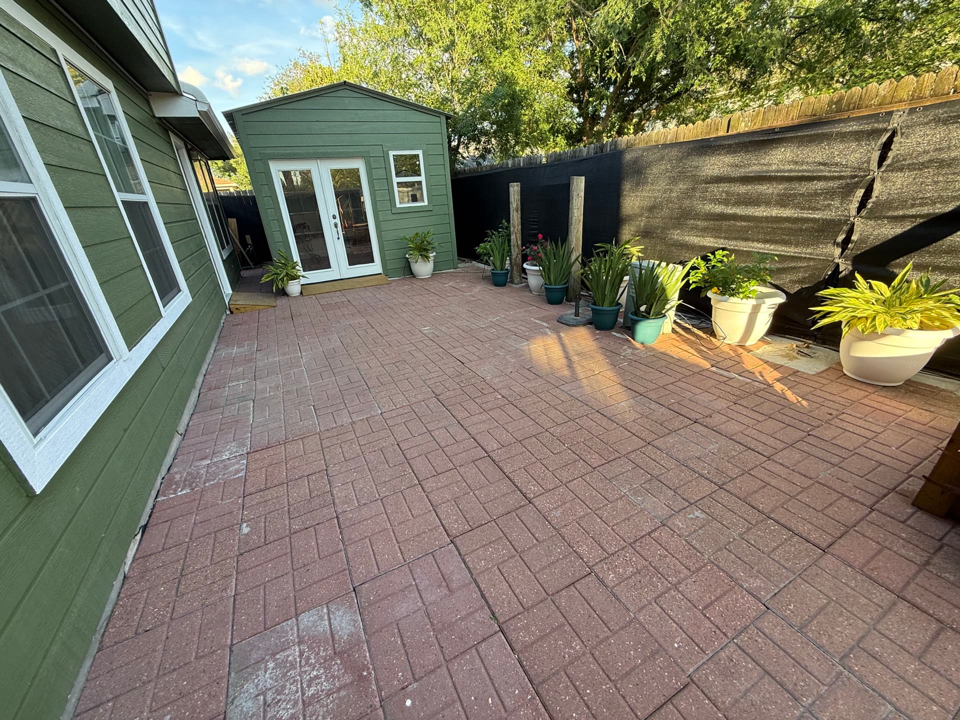 Backyard patio with green outbuilding and potted plants